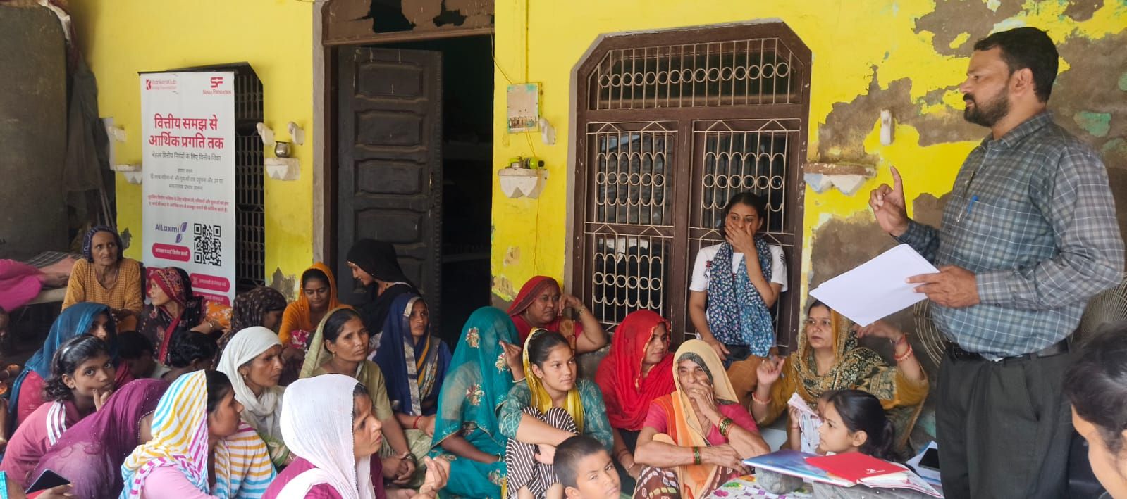 A BKIF trainer speaks to women seated outside a village home in Haryana